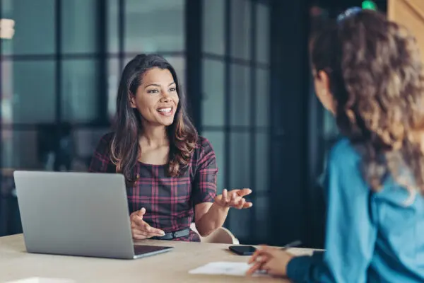 Woman sitting at table talking to another woman