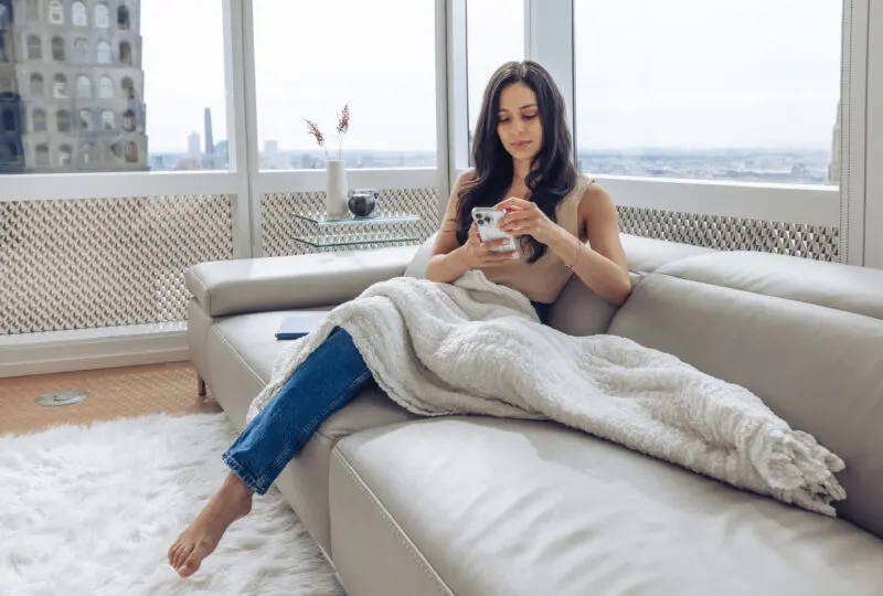 High-net-worth woman, sitting in her home looking at her phone