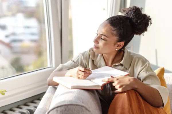 young woman sitting on couch journaling