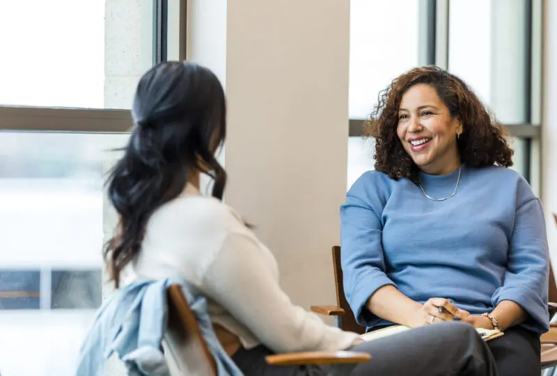 two woman sitting across from each other in a therapy session