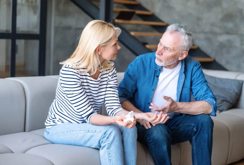 mature couple sitting on couch, talking through a disagreement