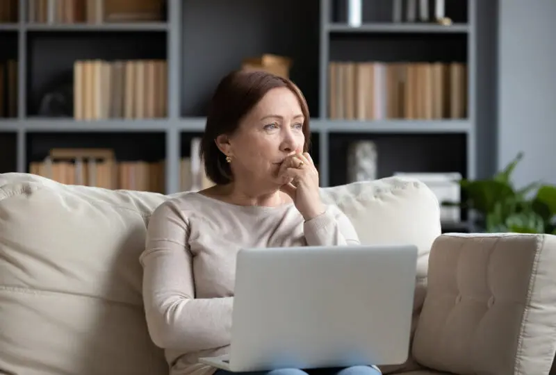 women sitting on couch looking out window, thinking