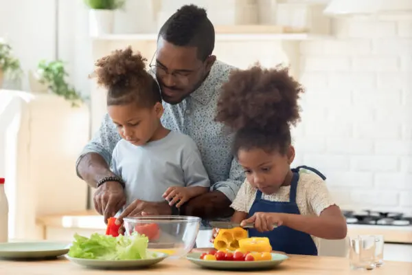 father with two children making food in the kitchen
