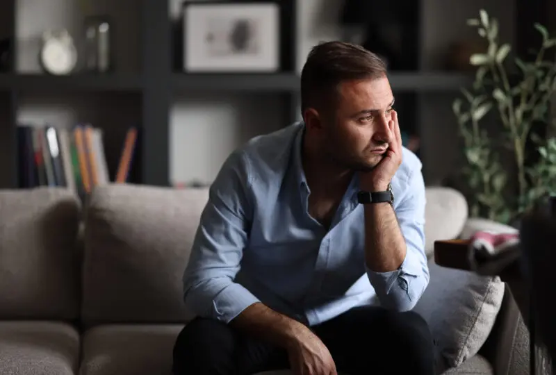 man sitting on couch looking out towards window