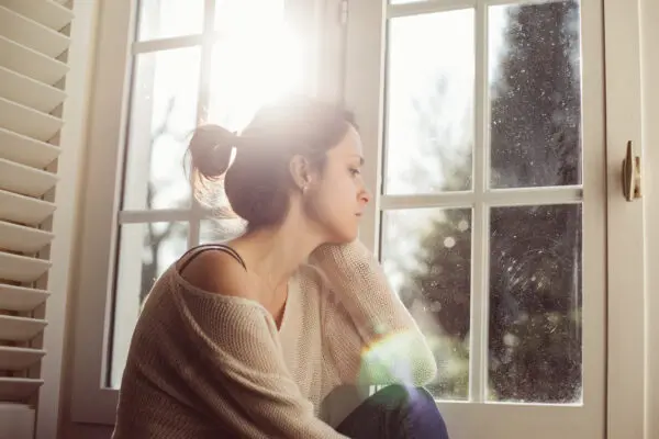 woman sitting in windowsill contemplating divorce