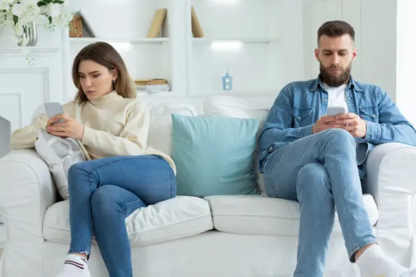 couple sitting on the couch distanced from one another