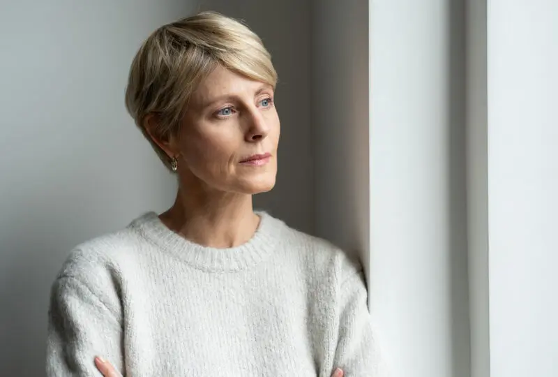 middle aged women, gazing out window, looking solemn