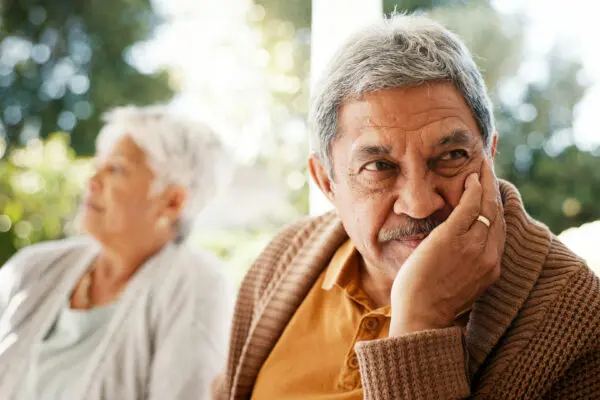 mature couple sitting outside on patio looking away from each other