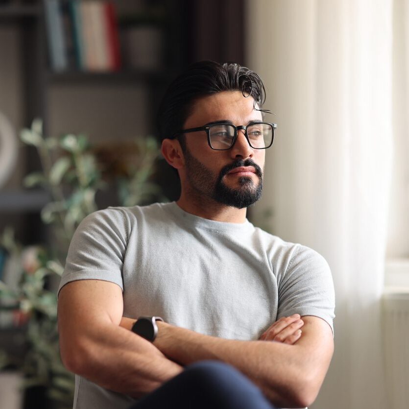 Man looking off into the distance, sitting in his home