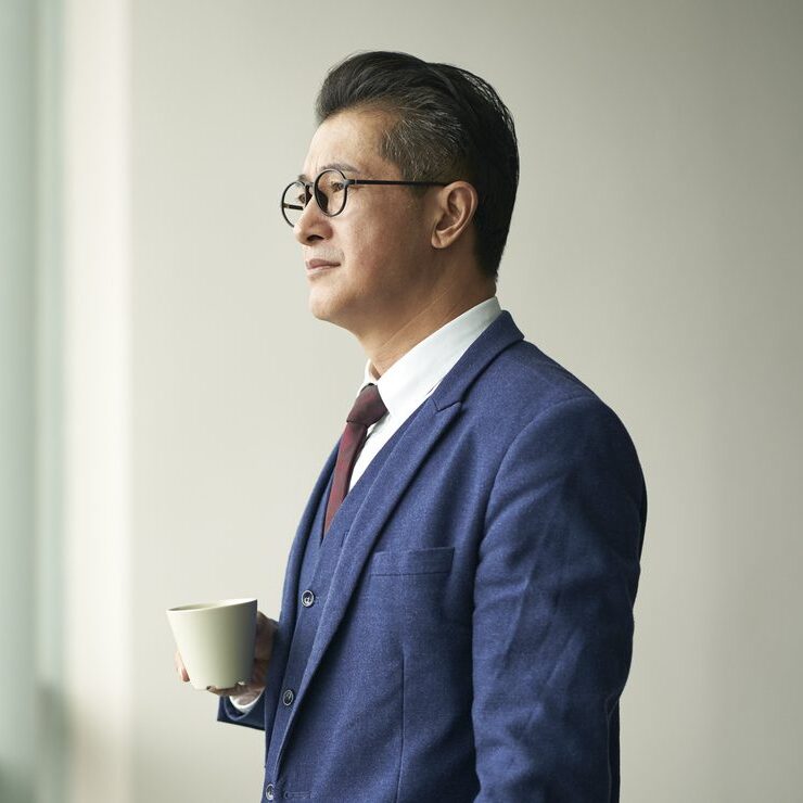 business man looking out window with cup of coffee