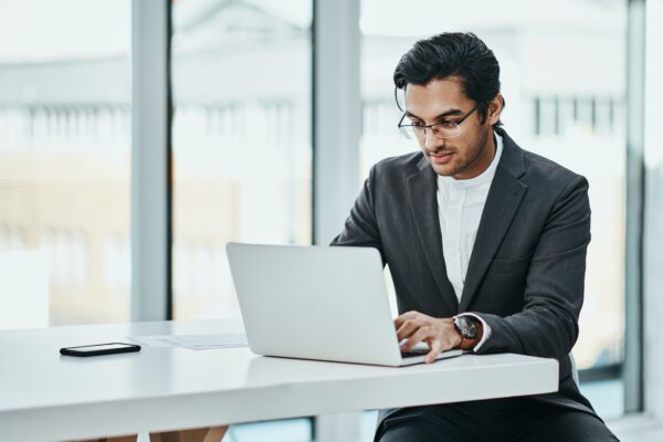 Young business man working in office, using a laptop