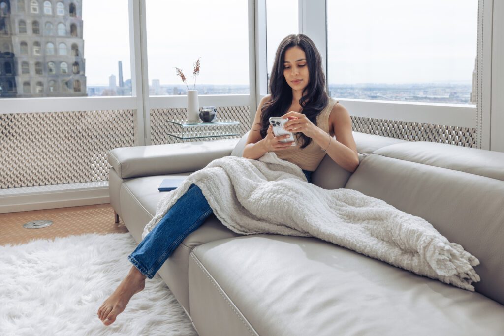 High-net-worth woman, sitting in her home looking at her phone