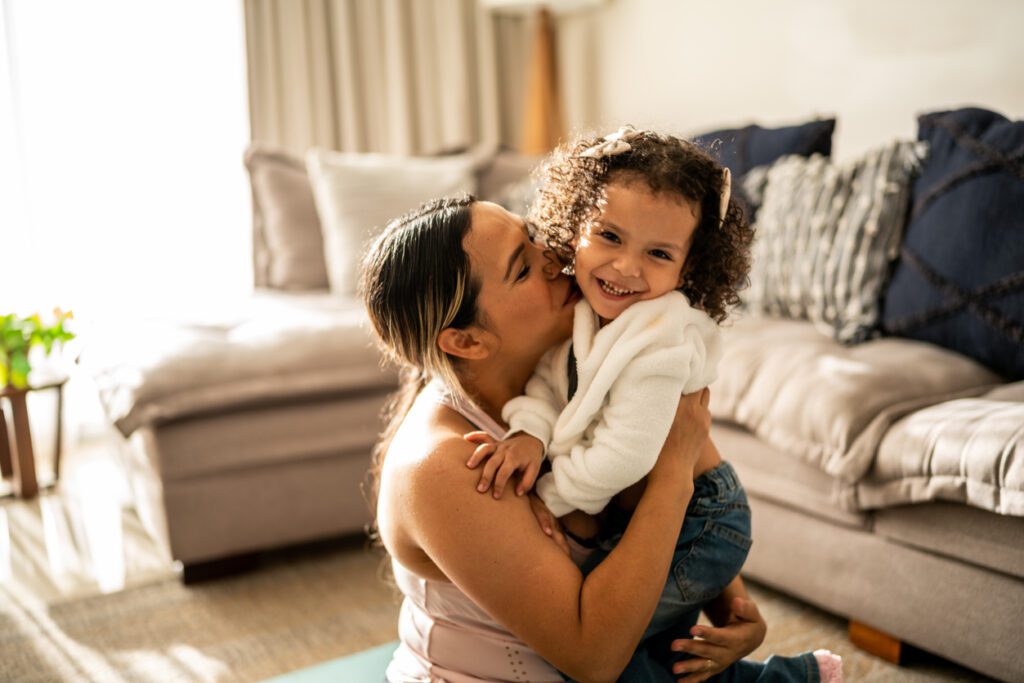 mom giving toddler daughter a kiss on the cheek