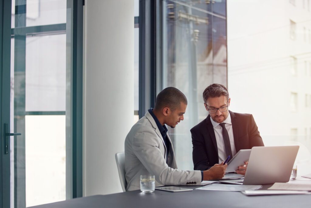 two men looking at papers at a conference table