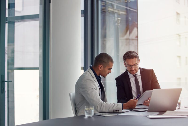 two men looking at papers at a conference table