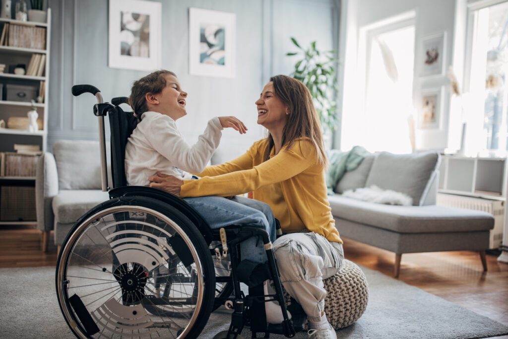 mother playing with young, wheel chair bound daughter in living room