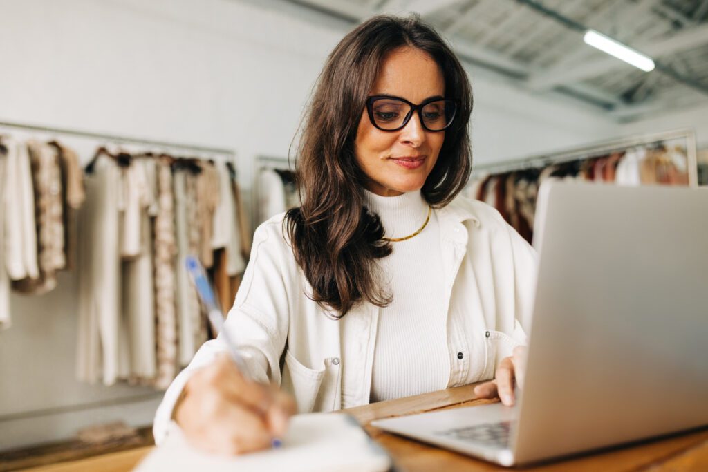 Business woman working on her laptop in her clothing store