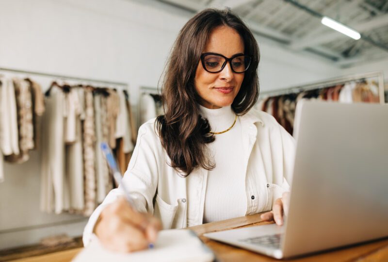 Business woman working on her laptop in her clothing store
