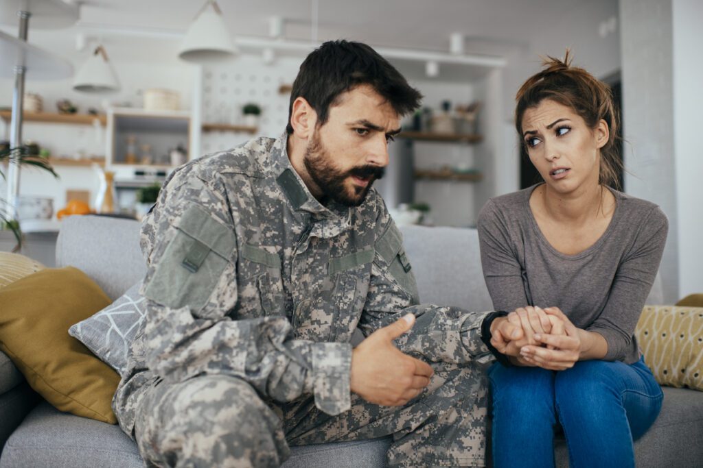 image of military husband and wife sitting on couch having serious conversation