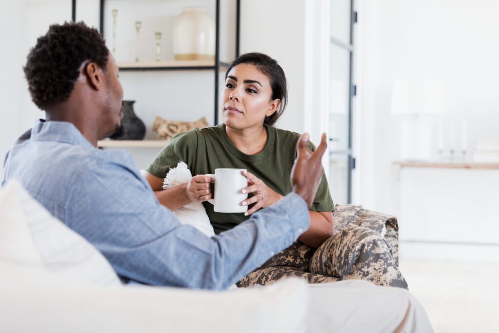 Military wife and husband having conversation on couch