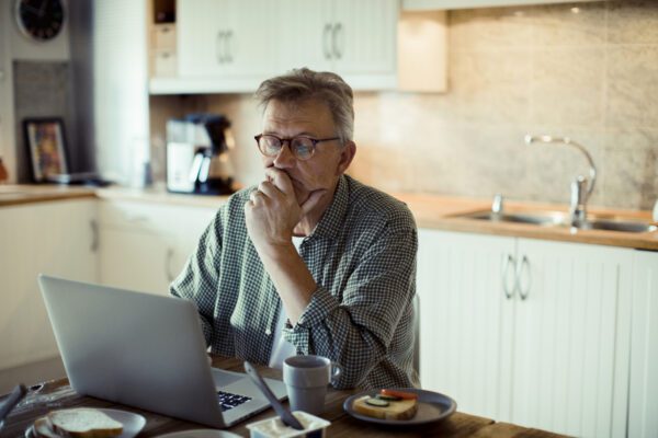 man looking at laptop at kitchen table