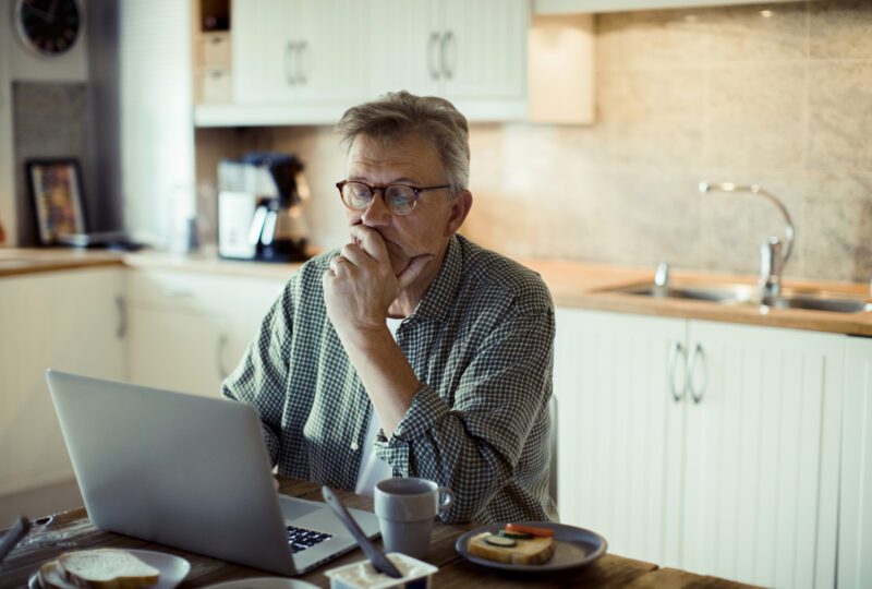 man looking at laptop at kitchen table