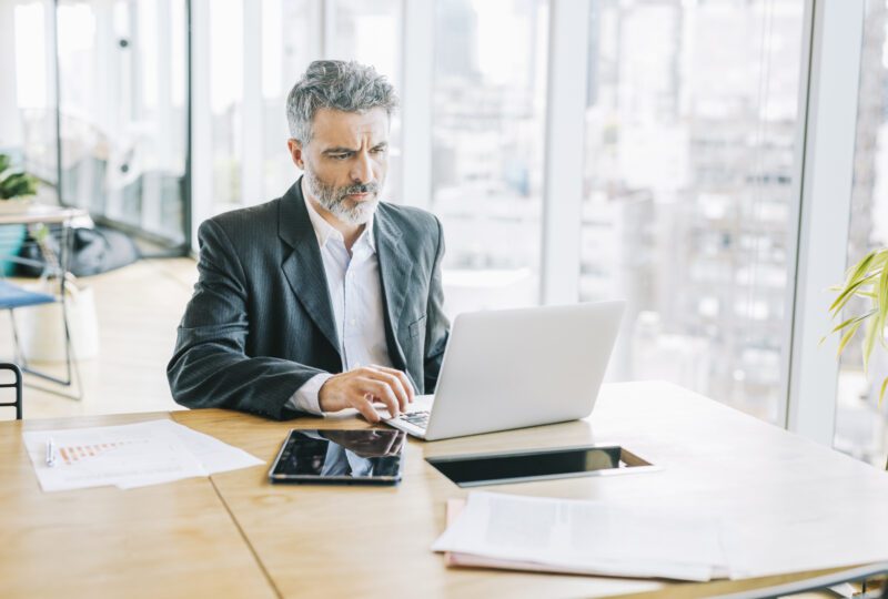 Business man in his office, looking at laptop