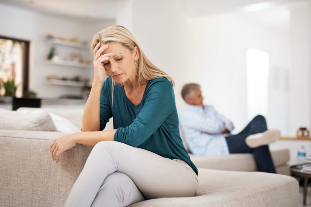 woman sitting away from husband on couch looking distressed