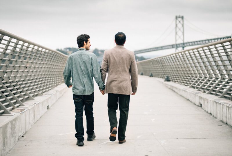 couple holding hands walking down a pier