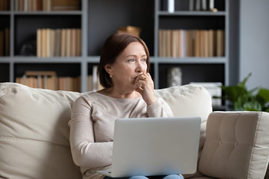 women sitting on couch looking out window, thinking