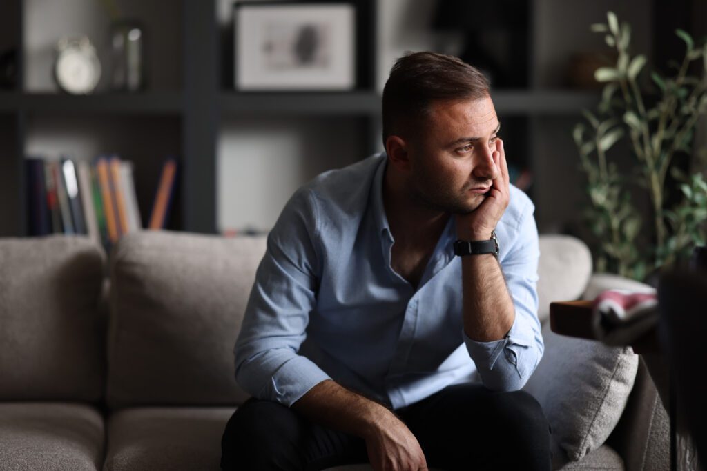 man sitting on couch looking out towards window