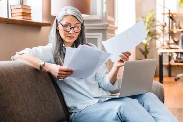 Asian women sitting on couch, looking at papers