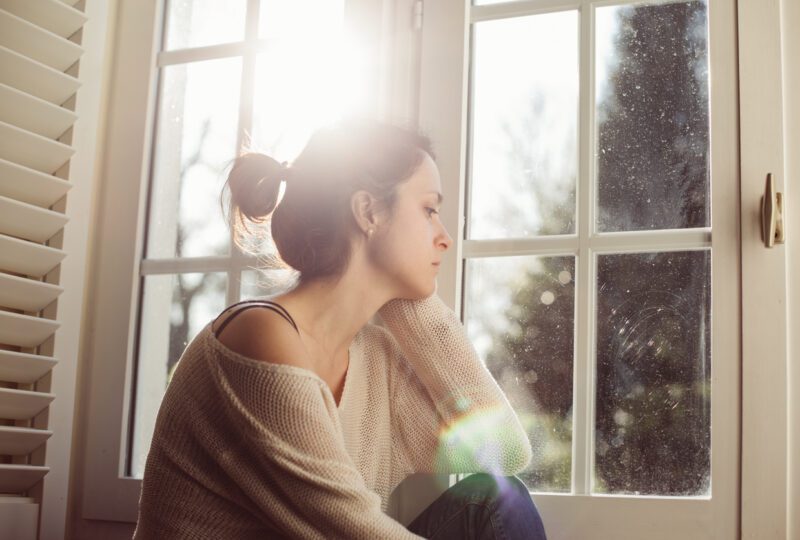 woman sitting in windowsill contemplating divorce