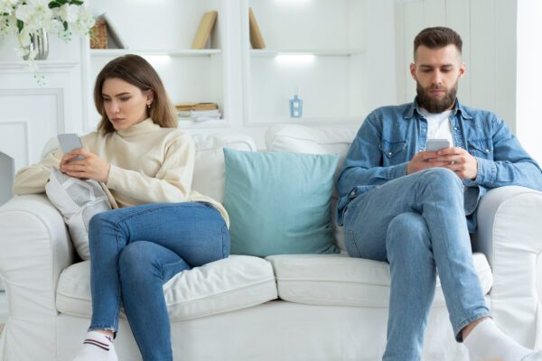 couple sitting on the couch distanced from one another