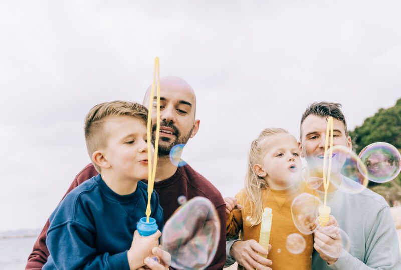 LGBT fathers with their two children, playing outside