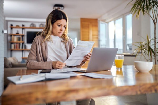woman sitting at dining table looking at financial statements