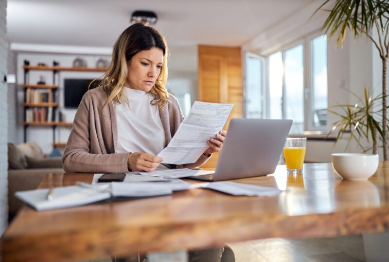 woman sitting at dining table looking at financial statements