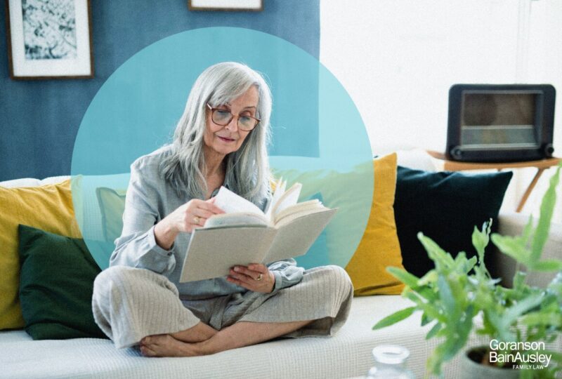 Elderly woman reading at home, representing thoughtful planning and financial considerations during divorce, including the division of pensions and retirement assets.