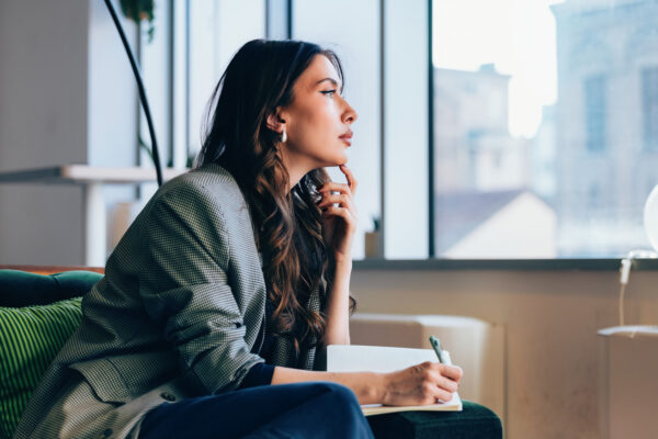 woman sitting with her journal, looking out window